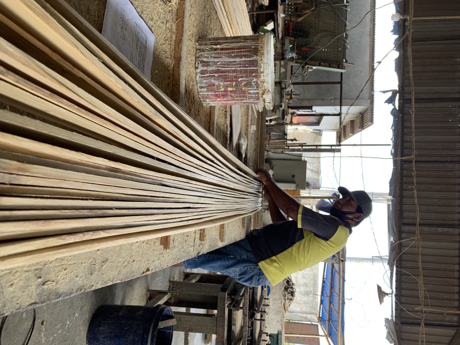 Two workers rolling eco-friendly adhesive across planed bamboo strips before they are pressed into a panel